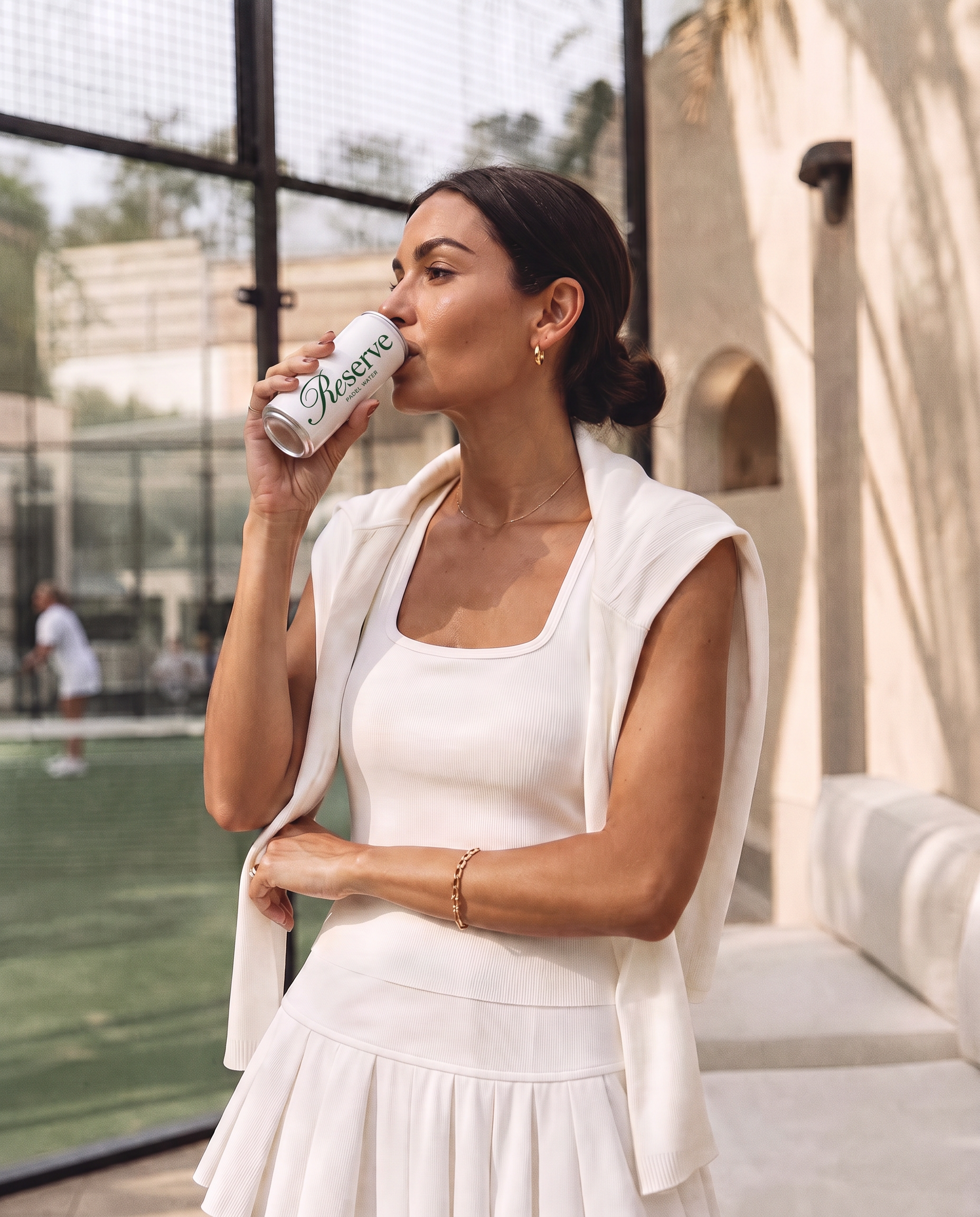 Reserve member courtside in tennis whites drinking Reserve canned water